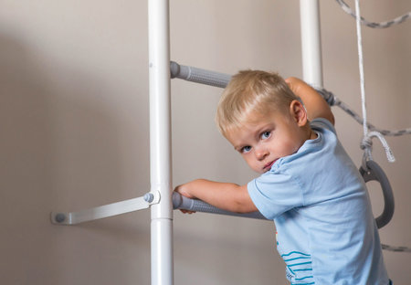 A small child boy climbs a Swedish wall or a sports complex. Climbing at home, the concept of...
