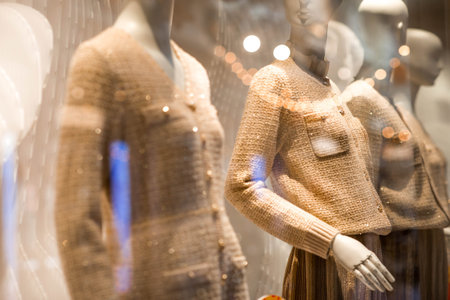An elegant showcase of a luxury store with stylish mannequins in clothes and evening lighting. The...