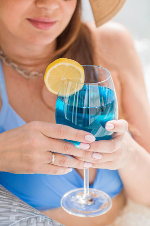 A young woman in a swimsuit and sunglasses in a Jacuzzi with a glass of cocktail on the background...