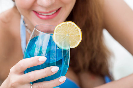 A young woman in a swimsuit and sunglasses in a bathtub with a glass of cocktail on the background of the pool. The concept of a summer vacation, vacation and foam party.の写真素材