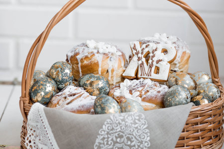 Banner for Easter. Easter eggs with gold accents and sweet pastries in a woven basket made of vines.