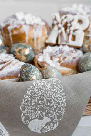 Banner for Easter. Easter eggs with gold, Easter cakes and gingerbread in the shape of the letters XB in a woven basket made of vines.の写真素材
