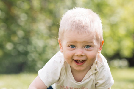 Portrait of a 1-year-old little boy outdoors. A happy child walks in the spring park. Happy...
