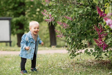 Portrait of a 1-year-old little boy outdoors. A happy child walks in the spring park. Happy...