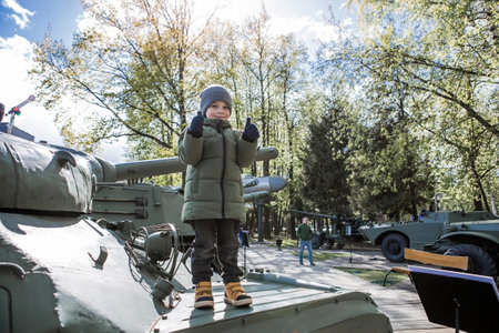 A 5-year-old little boy next to military equipment from the Great Patriotic War. A child stands on a tank.の写真素材