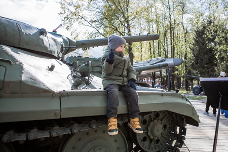 A 5-year-old little boy next to military equipment from the Great Patriotic War. A child is sitting on a tank.の写真素材