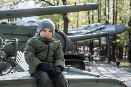 A 5-year-old little boy next to military equipment from the Great Patriotic War. A child is sitting...