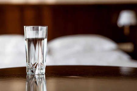 A glass of crystal clear fresh drinking water on the table in the interior of the hotel room.