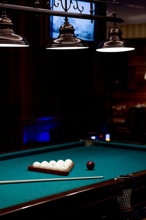 Red and white balls are lying on a green billiard table. Spending time at home playing a hobby...