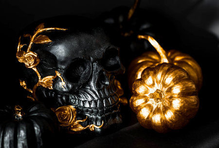 A mysterious black skull with golden roses and pumpkins for a Halloween or Day of the dead party on a black grunge background.の写真素材
