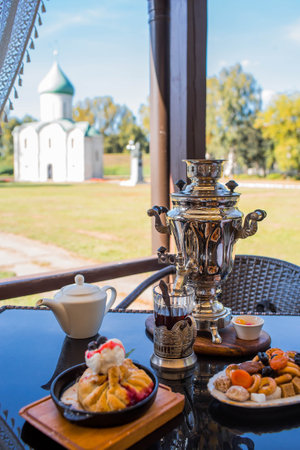 Russian traditions. Tea drinking over a samovar. Still life with bagels and Russian treats on the veranda against the background of the Transfiguration Cathedral in Pereslavl-Zalessky.の写真素材