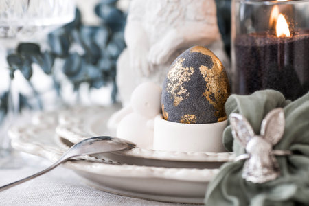 The banner. Table setting. A plate with a rabbit and a napkin, Easter eggs with gilding and a branch...