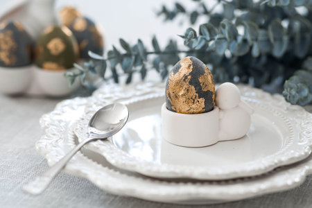 The banner. Table setting. An egg stand with a rabbit, Easter eggs with gilding and a branch of...