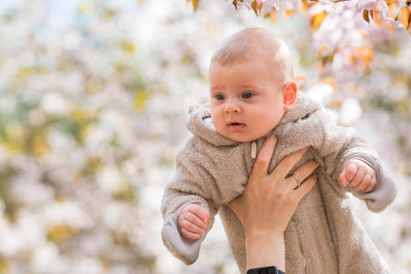 A charming child in nature among flowering trees. A 4-month-old child looks at the camera and...