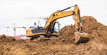 An excavator on a construction site in close-up. An excavator digs the ground with a bucket for construction. Heavy machinery for construction and landscaping.の写真素材