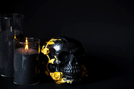 A mysterious black skull with golden roses and pumpkins for a Halloween or Day of the dead party on a black grunge background.の写真素材