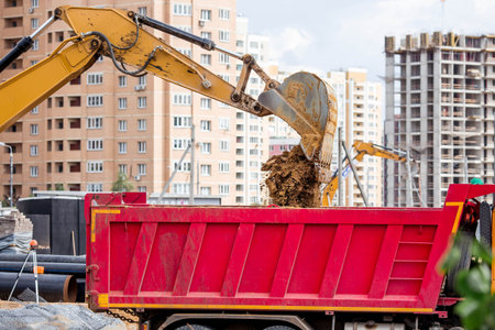 An excavator on a construction site in close-up. An excavator digs the ground with a bucket for...