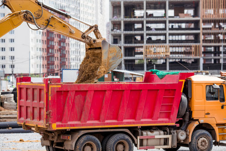 An excavator on a construction site in close-up. An excavator digs the ground with a bucket for...