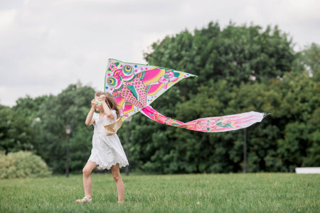 Children in the summer park. A beautiful girl is flying a kite in the fresh air. Warm family moments or a conceptual image for spending time outdoors.の写真素材