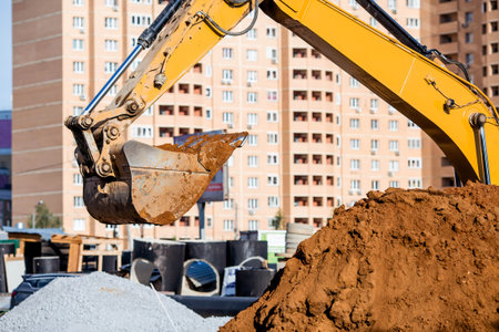An excavator on a construction site in close-up. An excavator digs the ground with a bucket for...