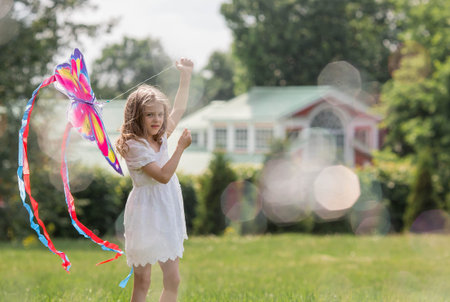 Children in the summer park. A beautiful girl is flying a kite in the fresh air. Warm family moments or a conceptual image for spending time outdoors.の写真素材
