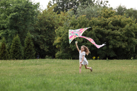 Children in the summer park. A beautiful girl is flying a kite in the fresh air. Warm family moments or a conceptual image for spending time outdoors.の写真素材