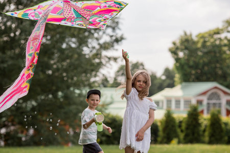 Children in the summer park. Children walk and fly a kite in the fresh air. Warm family moments or a conceptual image for spending time outdoors.の写真素材