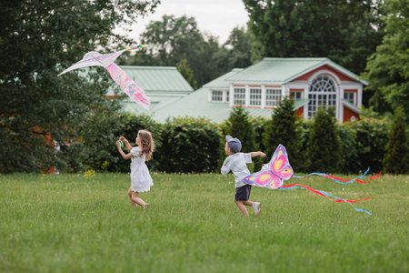 Children in the summer park. Children walk and fly a kite in the fresh air. Warm family moments or a conceptual image for spending time outdoors.の写真素材