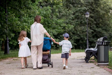 A family with three children. A mother with many children and toddlers in a summer park. Children are walking in the fresh air. Having many children and family values.の写真素材