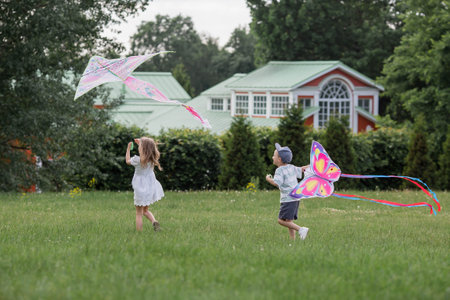 Children in the summer park. Children walk and fly a kite in the fresh air. Warm family moments or a conceptual image for spending time outdoors.の写真素材