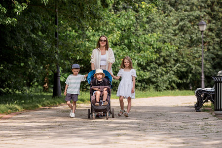 A family with three children. A mother with many children and toddlers in a summer park. Children are walking in the fresh air. Having many children and family values.の写真素材