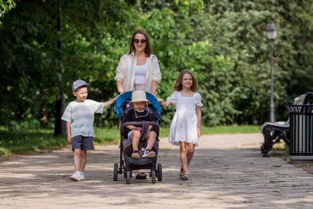A family with three children. A mother with many children and toddlers in a summer park. Children are walking in the fresh air. Having many children and family values.の写真素材