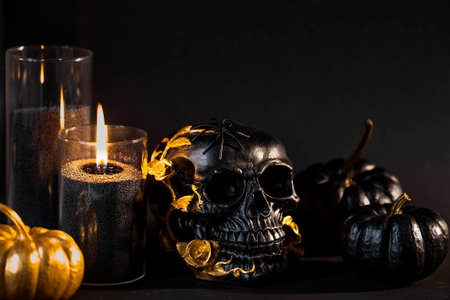 Halloween celebration. Black skull with golden roses, pumpkins, and black candles. Decor for the Day of the Dead or Halloween on a black background.の写真素材