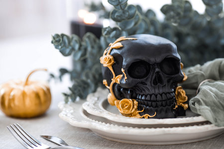 A mysterious black skull with golden roses and pumpkins on serving plates for a Halloween or Day of the Dead party.の写真素材