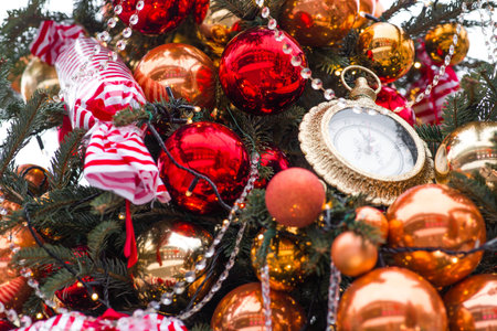Golden retro clock on a Christmas tree. The clock hands show 12 o'clock. Beautiful background for New Year's Eve or Christmas 2026.の写真素材