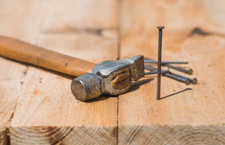 Close-up of a hammer and nails on wooden boards. Hand tools, old construction tools.の写真素材