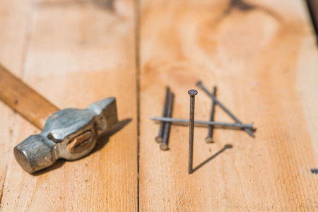 Close-up of a hammer and nails on wooden boards. Hand tools, old construction tools.の写真素材