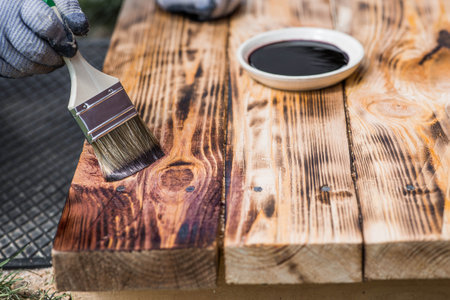 The procedure for protecting and coating wooden boards. A worker applies a protective wood stain with a brush. The process of restoring a hardwood flooring.の写真素材