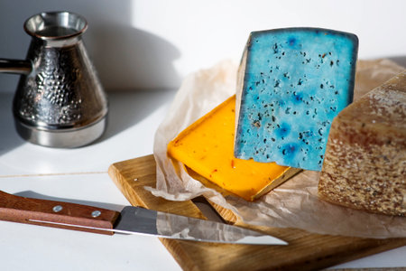 Pieces of fresh, aged, natural farm cheese on parchment paper on a wooden board. Unusual taste and quality of farm-fresh agricultural products.の写真素材