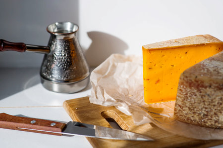 Pieces of fresh, aged, natural farm cheese on parchment paper on a wooden board. Unusual taste and quality of farm-fresh agricultural products.の写真素材