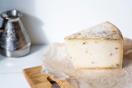 A piece of fresh, aged, natural farm cheese on parchment on a wooden board. Quality of farm-fresh agricultural products.の写真素材