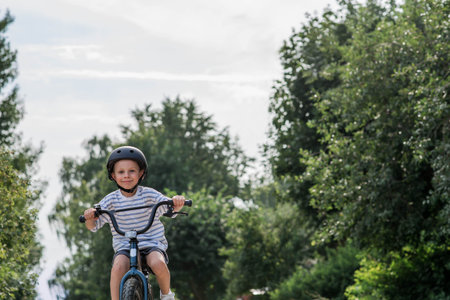 A beautiful 6-year-old boy riding a bicycle in a protective helmet outside. A happy child engaged in an active sport. Protection. Child safety.の写真素材