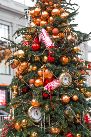 The clock hands on the dial show 12 o'clock. Golden retro clock on a Christmas tree. Beautiful...