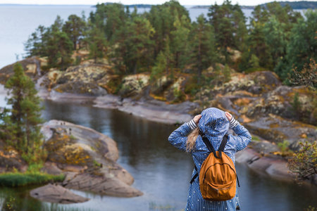 Tourism. Hiking. Ladoga skerries on Lake Ladoga. A female tourist in a raincoat with a backpack on...