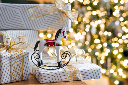 Stylish gift boxes and a horse on the background of a Christmas tree in a home interior of a living...