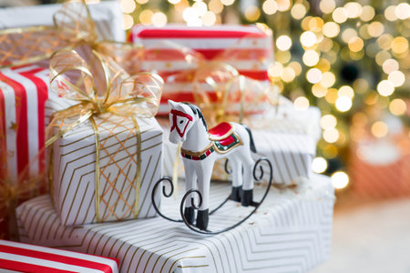 Stylish gift boxes and a horse on the background of a Christmas tree in a home interior of a living...