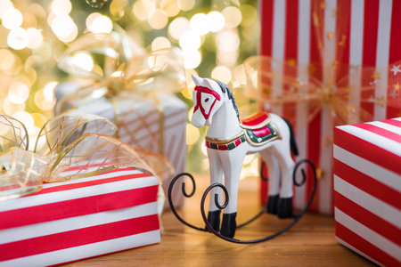 Stylish gift boxes and a horse on the background of a Christmas tree in a home interior of a living room. A cozy concept for the Christmas holidays. We are preparing gifts for our loved ones.の写真素材