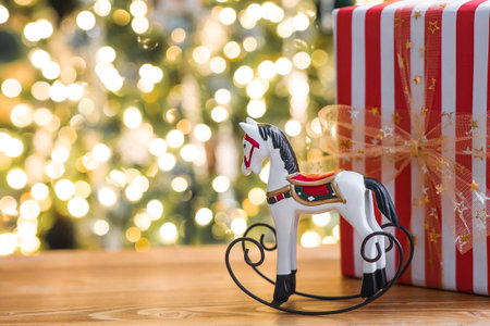 Stylish gift boxes and a horse on the background of a Christmas tree in a home interior of a living room. A cozy concept for the Christmas holidays. We are preparing gifts for our loved ones.の写真素材