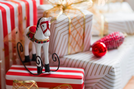 Stylish gift boxes and a horse on the background of a Christmas tree in a home interior of a living room. A cozy concept for the Christmas holidays. We are preparing gifts for our loved ones.の写真素材