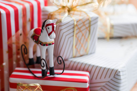 Stylish gift boxes and a horse on the background of a Christmas tree in a home interior of a living room. A cozy concept for the Christmas holidays. We are preparing gifts for our loved ones.の写真素材